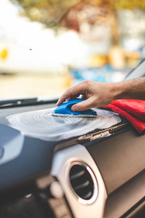 A person scrubbing the dashboard with Leather and Vinyl Interior Scrub.