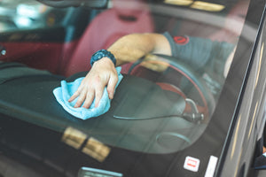 Person cleaning a car dashboard with a blue edgeless 300 towel.