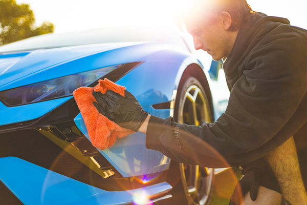 Microfiber towel drying off a blue car.