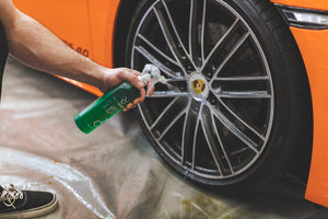 A person spraying an orange Porsche with Opticoat Power Clean.