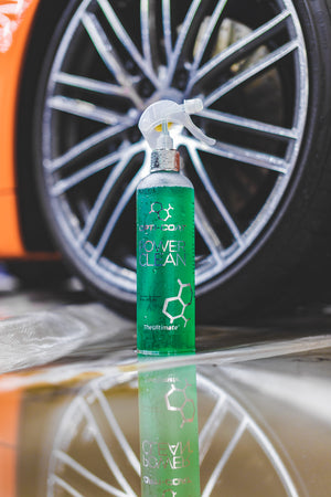 A spray bottle of Opticoat Power Clean in front of a car tire.