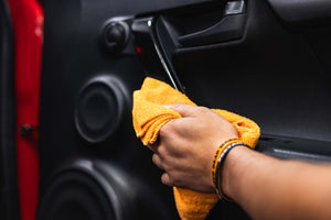 Person cleaning a car with Opti-Coat Protectant Plus and a orange microfiber.