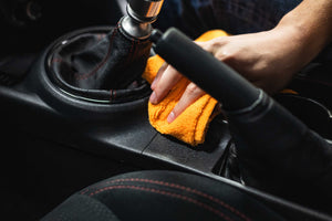 Person cleaning a car with Opti-Coat Protectant Plus and a orange microfiber.