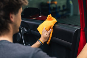 Person cleaning a car with Opti-Coat Protectant Plus and a orange microfiber.