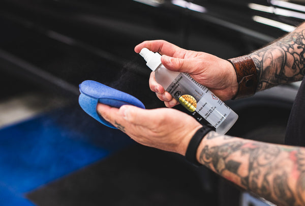 A person spraying Optimum Opti Seal on a blue sponge.