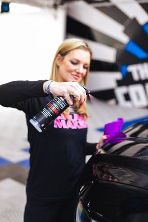 Person spraying P&S Inspiration Defender onto the hood of a car with a purple microfiber towel.