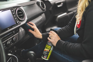 A person spraying P and S Dynamic Dressing on the center console of a car.