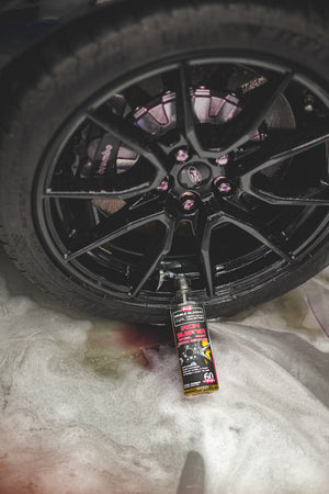 A spray bottle of P and S Iron Buster laying on the rim of a tire.