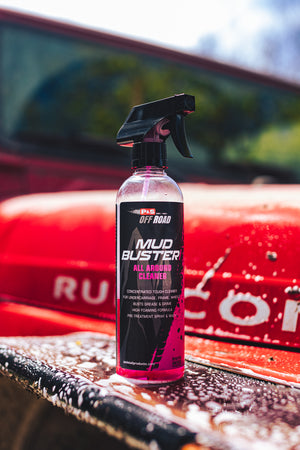 A spray bottle of P and S Mud Buster on the hood of a red jeep.