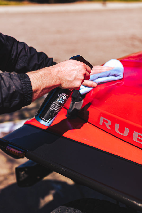 A person spraying a red Jeep with P and S Pit stop.