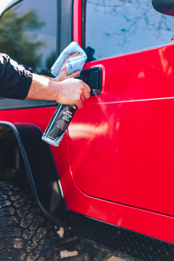 A person spraying a red Jeep with P and S Pit stop.