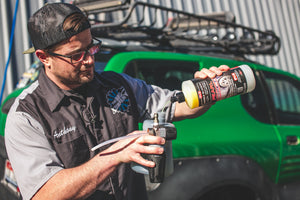 A person pouring P and S Pearl into a spray bottle with a green car in the background.