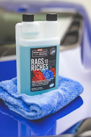 A bottle of P and S Rags to Riches sitting atop a folded blue towel on top of a blue car.