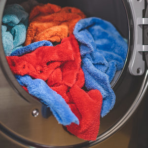 A drying machine full of Red, Orange, and Blue towels.