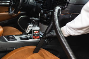 Person cleaning car interior with a bottle of P&S Release.