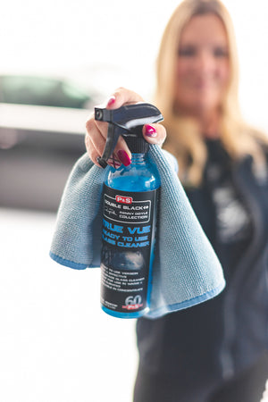 A closeup of a person holding a blue towel and a spray bottle of P and S True Vue.