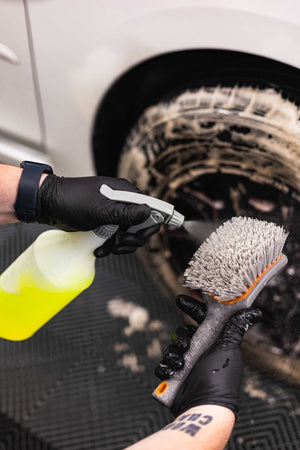 Person spraying a spray bottle filled with P&S Undressed onto a Detail Factory Wheel Brush.