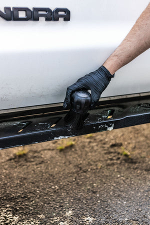 Person cleaning a car step with a Detail Factory Curveball.