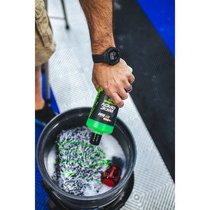 A person pouring P and S Wide Open into a bucket that has a TRC Mitt and water in it.