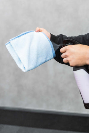 Person spraying a blue FTW microfiber with an iK Sprayer.