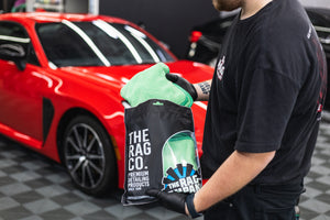 Person pulling out a green FTW front the packaging with a red car in the background.