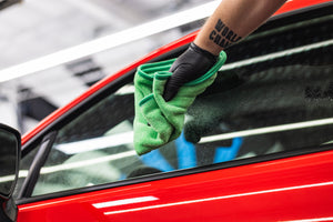 Person cleaning a car window with a green FTW microfiber.