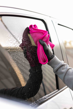 A person using a Premium FTW Pink Towel to wipe the wet window of toyota tundra. 