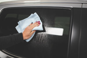 Using a blue Premium Glass & Window microfiber towel from The Rag Company to clean the window of a Toyota Tacoma