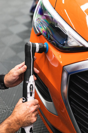 A person using a rupes da coarse pad on a polisher.