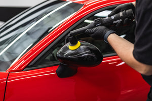 Person cleaning a car side mirror with a rupes ibrid nano