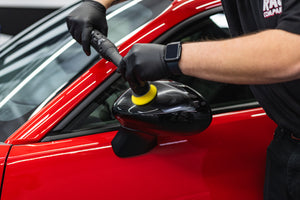 Person cleaning a car side mirror with a rupes ibrid nano