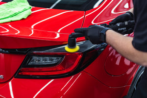Person cleaning a car rear tailight with a rupes ibrid nano