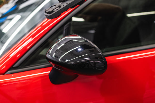 Close-up of a car's side mirror on a red vehicle