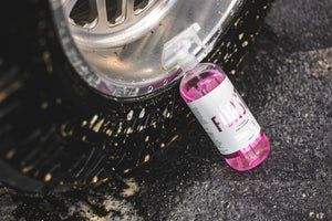 A spray bottle of Stjarnagloss Forst leaning against a car tire.