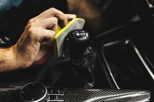 A person using a tool to clean the gear shift of a car.