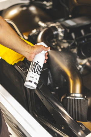 A person spraying Stjarnagloss Mork onto a vehicles engine.