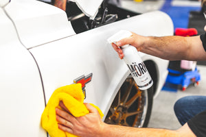 A person spraying Stjarnagloss Mork onto the siding of a white car.