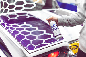 A person spraying Stjarnagloss Slike on the hood of a purple car.