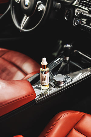 A bottle of Stekare Gold Air Freshener on the center console of a car.