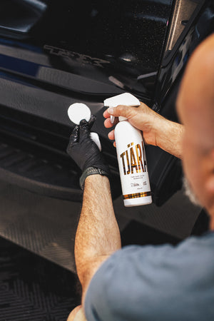 A person spraying a small white scrubber with Inni Interior Cleaner.