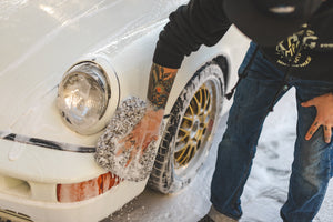 A person scrubbing a foamy car with a soaking wet Cyclone towel.