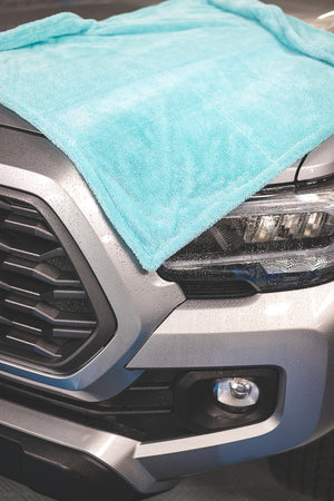 A light blue towel laid across the hood of a grey Toyota Tacoma.