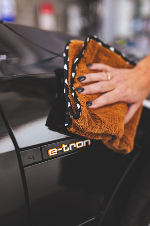 Orange Wolf Pack Towel wiping off a black e-tron. 