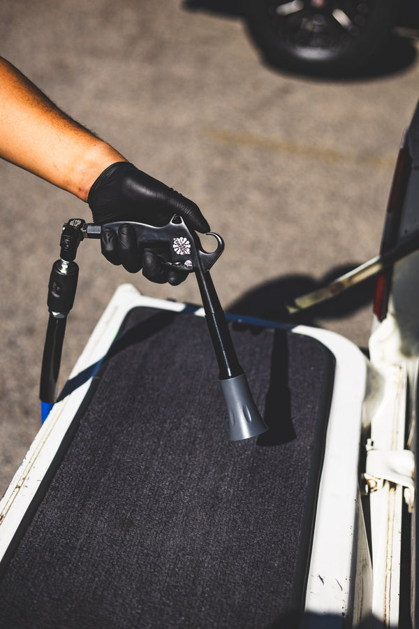 A closeup of a person using the Ultra Air Blaster to clean the floor of a car.