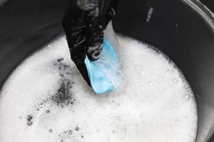 The Rag Company Ultra Clay Bar being dumped into a soapy bucket.