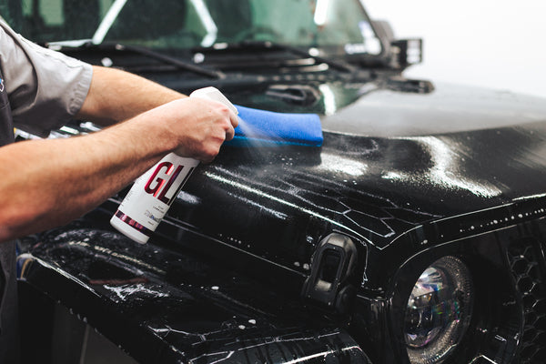 A person spraying Stjarnagloss on a black jeep and wiping it with the Ultra Clay Mitt.