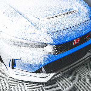 A blue car with soap on it from using a TRC Ultra H2O Foam Cannon to spray soap onto it.