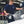 A person using a TRC Ultra H2O Foam Cannon to spray soap onto a blue car.