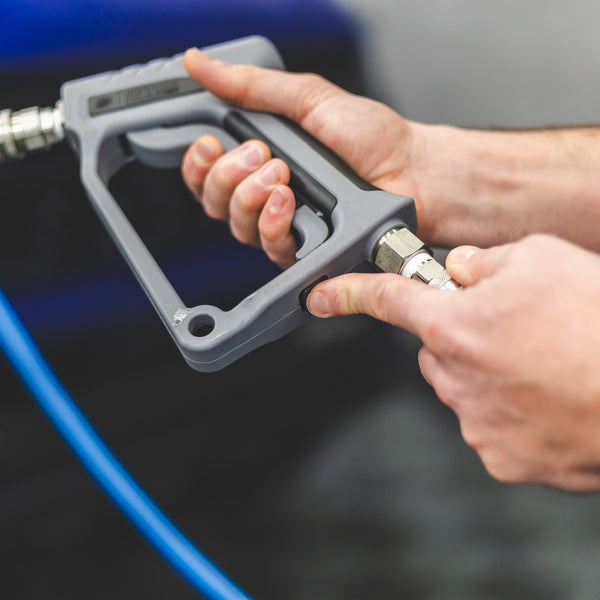 A person connecting a TRC Ultra H2O Spray Gun to a pressure washer hose.