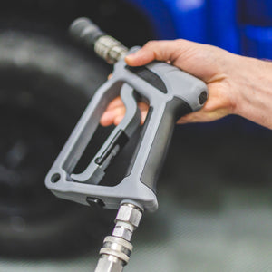 A person holding a TRC Ultra H2O Spray Gun connected to a pressure washer hose.